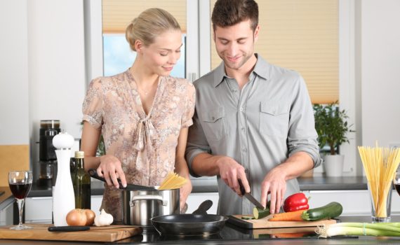 two happy people making dinner