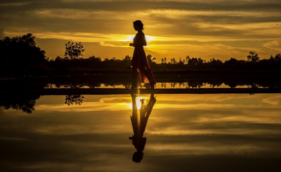 Woman walking during sunset by the water to represent energy and productivity